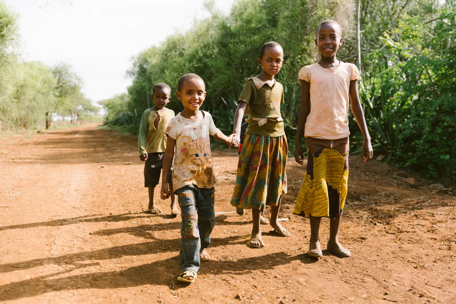 Children walking home along a red-earth road